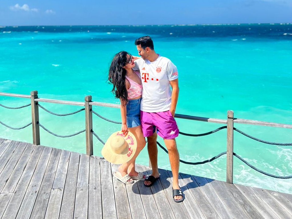 A couple on a wooden jetty above bright turquoise water