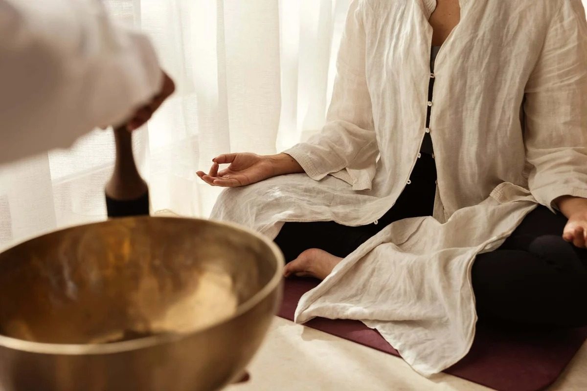 A guest seated in meditation while a singing bowl is played, Jayasom
