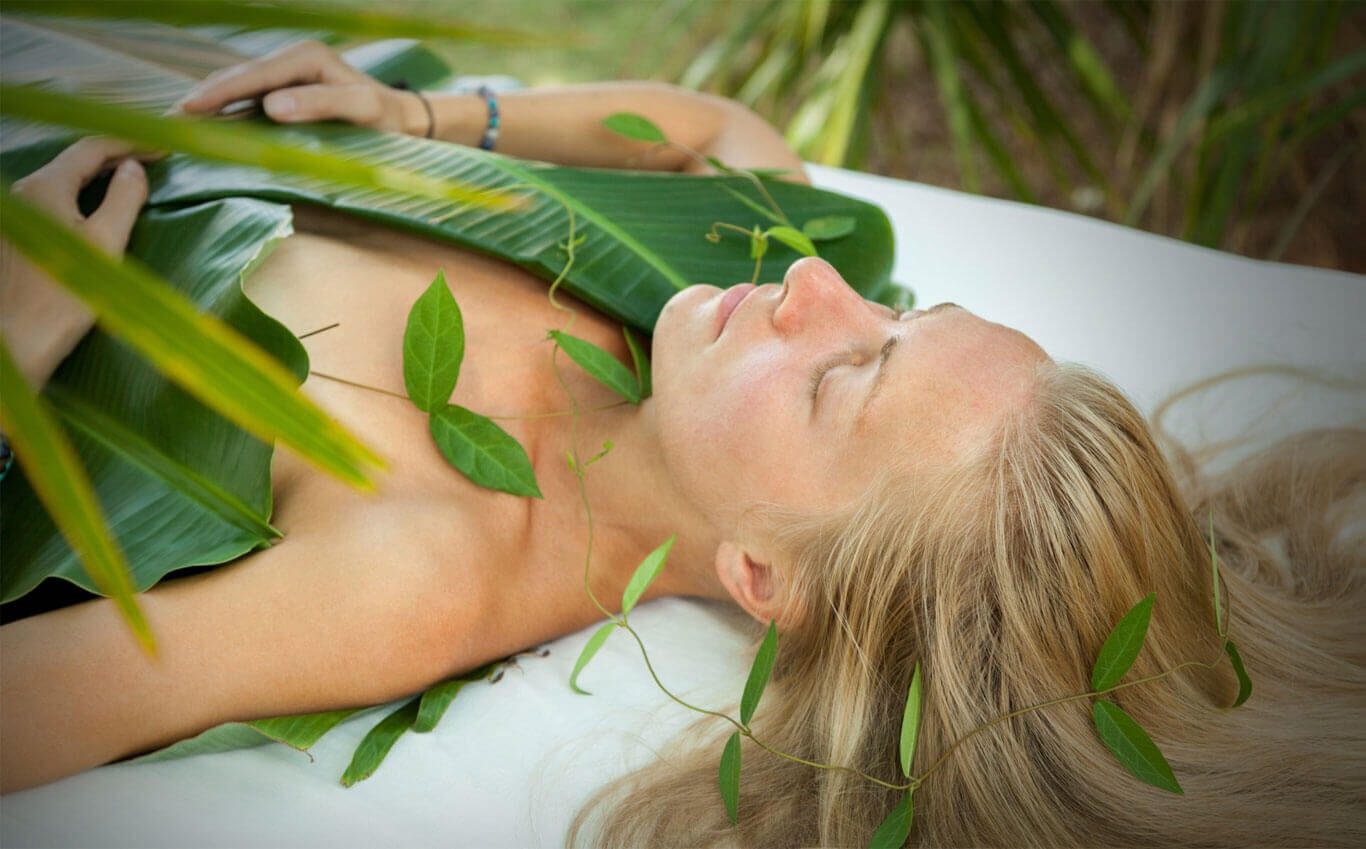 A guest resting with closed eyes among fresh leaves during a natural-medicine treatment, Prakriti Shakti, CGH Earth