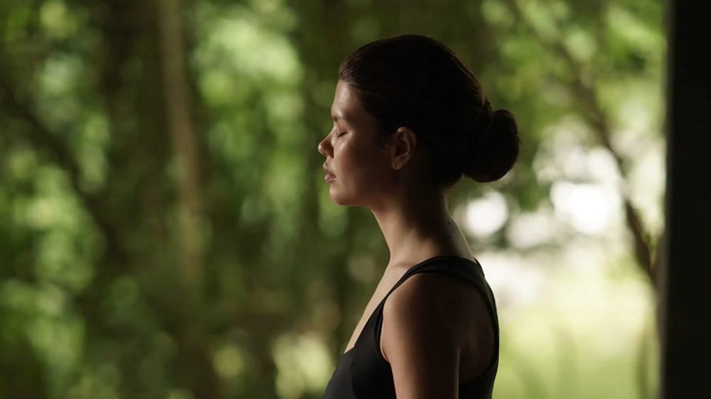 A woman in profile with closed eyes, in meditation among the trees, Santani Wellness